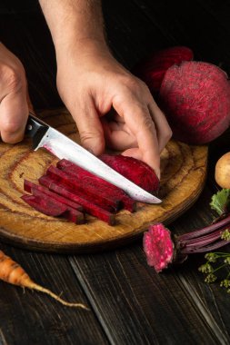 Aşçı lezzetli borş hazırlamak için pancar kökünü bıçakla keser. Ukrayna ulusal mutfağı.