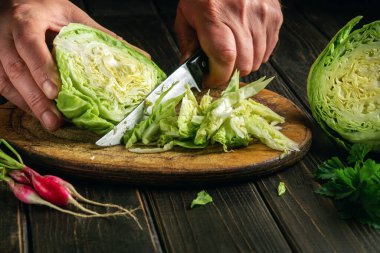 Aşçı, vejetaryen yemeği hazırlamadan önce kesme tahtasındaki bıçakla taze lahana keser..