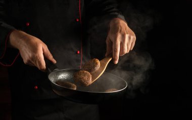 Ahşap bir aletin üstünde ızgara ızgarada biftek. Bir aşçının elinde tavada sığır eti ya da domuz pirzolası pişirmek. Menü veya tarif için siyah boşluk