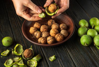 Şef mutfak masasındaki yeşil cevizleri soyar. Yemek tarifinden önce yemek pişirirken ellerin yakın plan çekimi