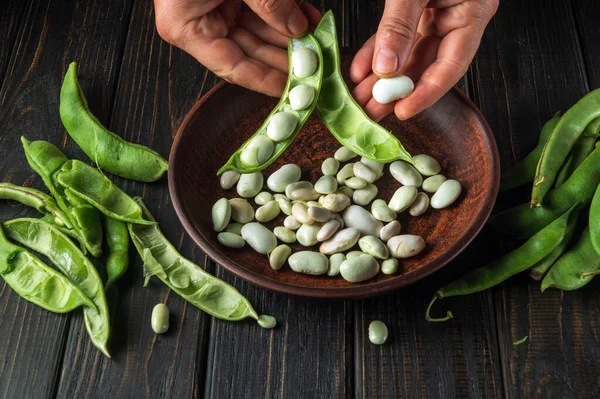 Close-up of the chef hands on the kitchen table are cleaning green beans. Organic peasant food after harvest.