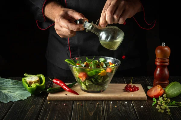 The cook prepares a fresh vegetable salad for a diet breakfast or dinner. Menu concept for hotel on black background