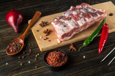 Kesme tahtasında çiğ domuz pirzolası ve baharat. Lokanta için lezzetli yemekler pişirmeye hazırlanıyorum..