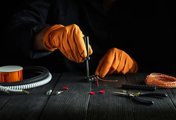 Close-up of hands of a master electrician during work. Repair of electrical equipment or electrical connection in the workshop