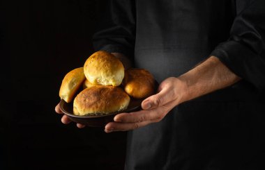 Fırıncının elindeki tabakta dereotu olan köfteler ya da turtalar. Ukrayna ulusal yemeği. Reçete için siyah boşluk.