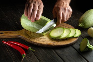 Aşçı lezzetli bir öğle yemeği veya kahvaltı hazırlamadan önce sebze iliğini bıçakla küçük parçalara ayırır.