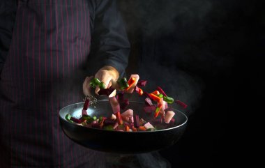 Şefin tavasında sebze pişirmek siyah arka planda fotokopi alanı ile. Beslenme konsepti. Otel için sebze menüsü.
