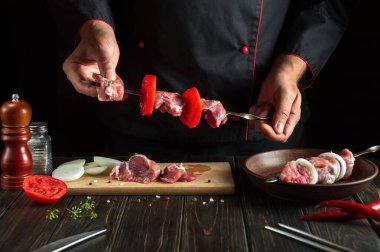 Restoran mutfağında bir şefin elleriyle çiğ dana etinden şiş kebap pişirmek. Asya geleneksel mutfağı