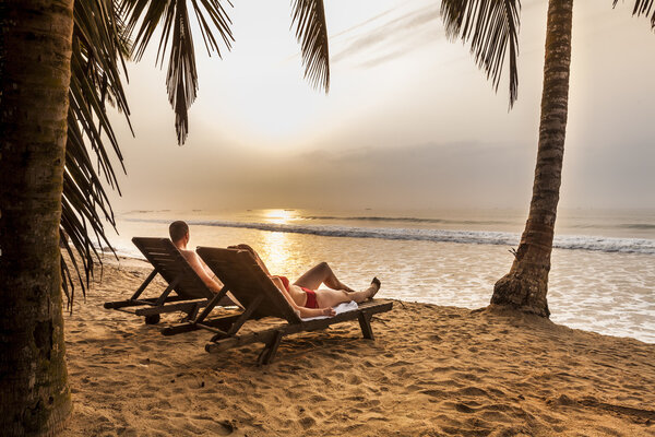 Couple on the sunbeds on the tropical beach