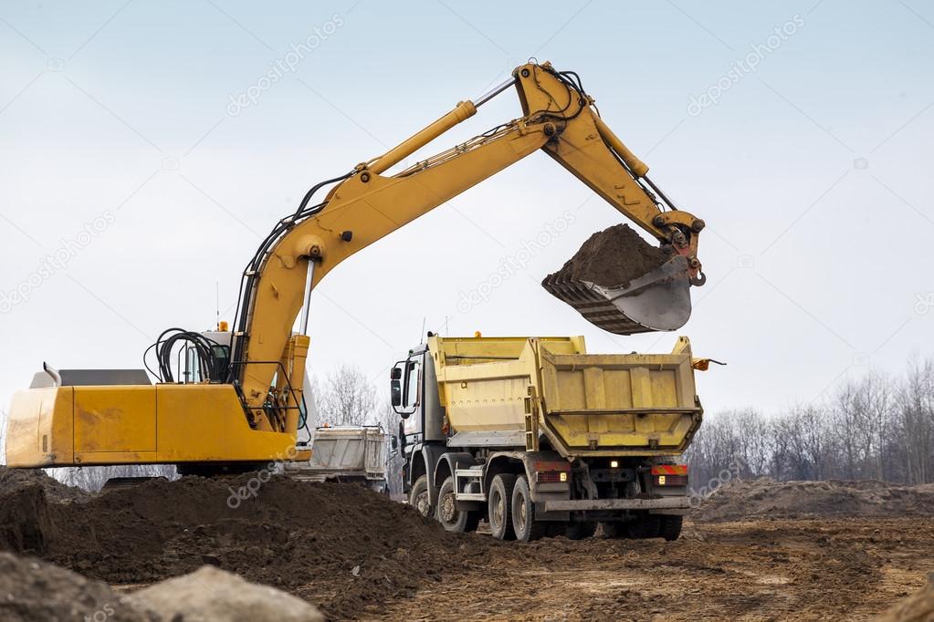 Digger loading trucks with soil