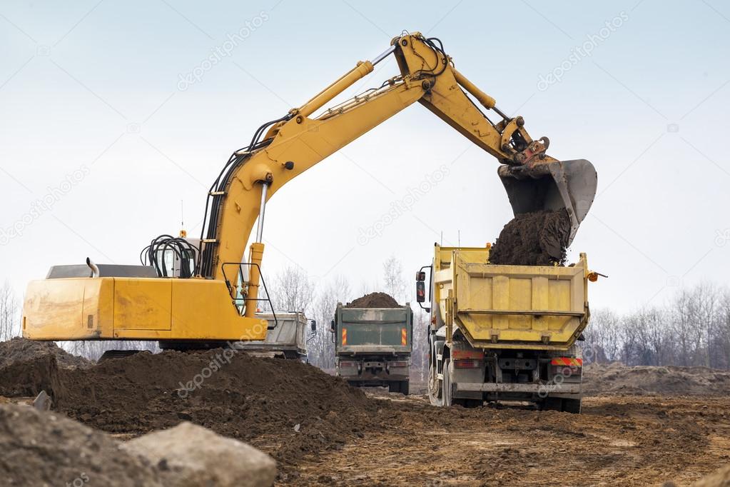 Digger loading trucks with soil