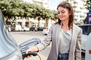 Kadın şehir ortamında elektrikli araba şarj ediyor, Faro, Portekiz