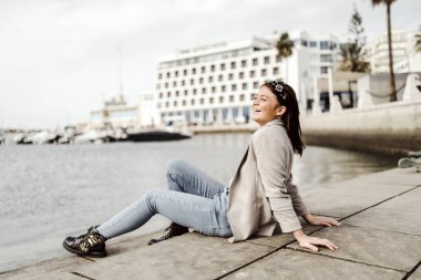 Faro, Algarve, Portekiz 'de marinada oturan genç bir kadın.