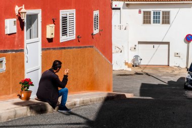 A local man smoking a cigarette sitting in front of his house in the street of Pozo Izquierdo, Canary Islands, Spain