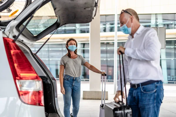 Havaalanında koruyucu maskeli bir yolcuya yardım eden bir taksi ya da Uber sürücüsü.