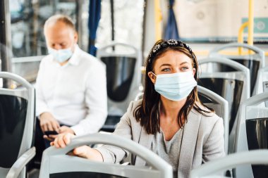 Kamu otobüsüyle gidip gelen koruyucu maskeler takan gezginler