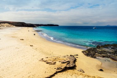 Sailing boat and sandy beach called Playa del Pozo in Los Ajaches National Park on Lanzarote, Canary Islands, Spain