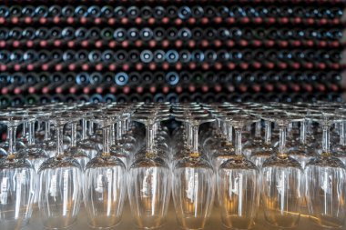 Empty wine glasses with many  stacked bottles as a background - preparation to wine tasting in the winery of Lanzarote, Spain