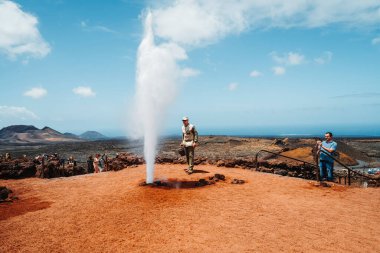 Timanfaya Ulusal Parkı, İspanya - 24 Nisan 2022: Ranger volkanın sıcaklığını hemen buhar haline gelen suyu dökerek gösteriyor 