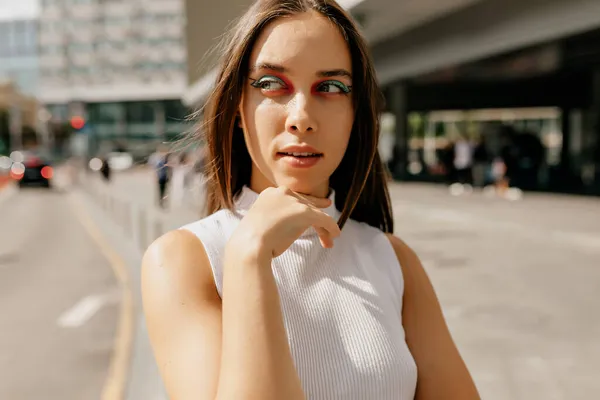 Mujer con estilo de confianza con la moda maquillaje mirando a un lado en el sol en el fondo de la ciudad —  Fotos de Stock