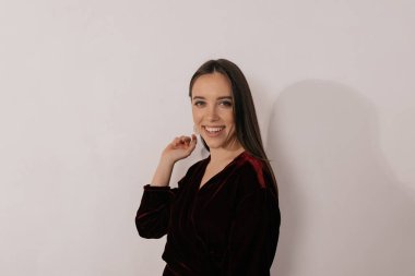 Çekici elbiseli ince stil sahibi kadın beyaz arka planda gülüyor. Partiye hazırlanan güzel bir kızın fotoğrafı.