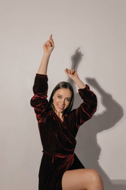 Kahverengi saçlı, gülümseyen, neşeli elbiseli, el ele tutuşan ve izole edilmiş arka planda kameraya bakan bir kız.