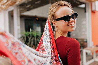 Mutlu gülüşü olan sevimli bir kızın arka portresi. Uçan eşarpla kameraya dön. Şehirde gün ışığında mutlu duygularla yürüyen güzel bir kız. Yüksek kalite fotoğraf