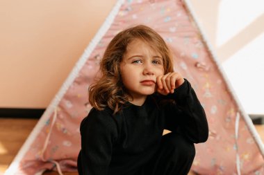 Yakından bakınca, siyah ev kıyafetli sevimli küçük bir kız çocuğunun çadırının önünde kameraya poz veriyor. - Evet. Yüksek kalite fotoğraf