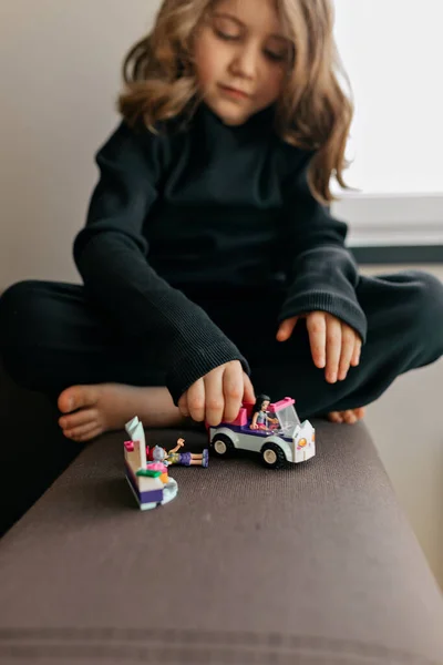 波状の髪型の素敵な愛らしいかわいい女の子は自宅でおもちゃで遊んでいます 愛らしい少女が車で遊んでいる ロックダウン中に家にいる子供たちのための創造的なゲーム 高品質の写真 — ストック写真