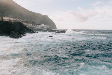Mavi heyecanlı okyanus, kayalar ve açık mavi gökyüzü. Gün batımında kayalarla okyanus manzarası. Seyahat et. Vahşi doğa. Yüksek kalite fotoğraf