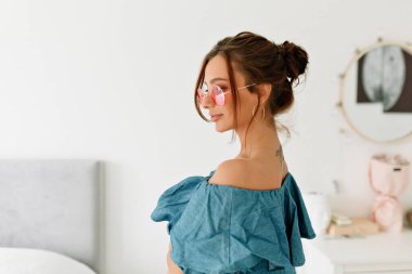 Güneş yanığı tenli, koyu renk saçlı hoş bir hanımın kapalı mekan portresi modern şık bir dairede poz veriyor. Duygu kavramı, yüz ifadesi.