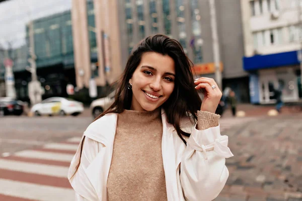 Siyah saçlı ve harika gülüşlü güzel bir kadının açık hava portresi sokakta yürüyor.