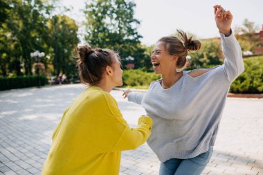  Birlikte vakit geçiren gülen iki kız kardeşin açık hava portresi. Heyecanlı kızlar parkta dans edip eğleniyorlar.. 