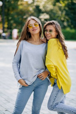 Şehrin sokaklarında birbirine sarılan iki güzel kızın yakın plan portresi. Güzel, neşeli genç kadınların yakın plan portresi. Eğleniyor, gülümsüyor, güzel anlar, en iyi arkadaşlar..