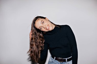 Happy pretty woman with wavy long dark hair wearing black pullover is dancing and having fun over isolated background. Indoor photo of european cute girl posing at camera