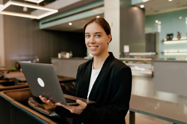 Harika bir stil sahibi bayan rahat ofisteki iş arkadaşlarıyla internette sohbet ediyor. Beyaz gömlekli gülümseyen kızın kapalı mekan portresi ofiste kahve molası veriyor.. 