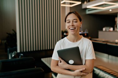 Koyu saçlı, beyaz tişörtlü, harika gülümseyen güzel bir bayan. Gözleri kapalı ve mutlu bir şekilde gülümsüyor.. 