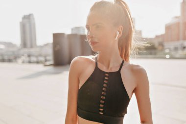 Genç ve güzel fitness kızının yakın plan fotoğrafı sabah güneş ışığında şehir manzaralı spor egzersizleri yapıyor..