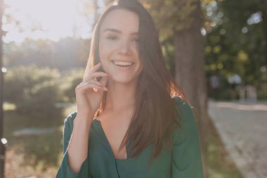 Mutlu gülüşlü harika bir kadın gün ışığında kameraya poz veriyor. Şehir arka planında sokakta yürüyen uzun siyah saçlı zarif bir kızın portresi. - Evet. Yüksek kalite fotoğraf