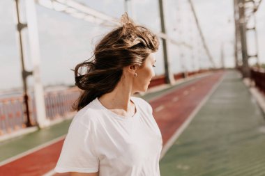 Saçları dökülen güzel bir kızın portresini yakından çek. Kız köprüde yürüyor ve yana bakıyor. Yüksek kalite fotoğraf