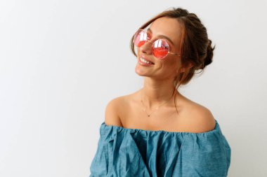 Mutlu beyaz bir kız mutlu bir gülümsemeyle yana bakıyor. Parlak makyajlı esmer, neşeli bir şekilde gülümsüyor, mavi tişört giyiyor..