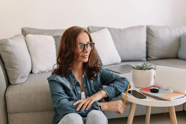 Şık Avrupalı kadın, dalgalı siyah saçlı, muhteşem saçlı, güneşli bir sabahta evde çalışırken yerde oturuyor. 
