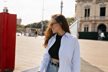 Uzun dalgalı saçlı, açık renk elbiseli güzel bir kızın profil portresi. Mutlu bir gülümseme ve açık havada yürümekten zevk alan bir kenara bakıyor.. 