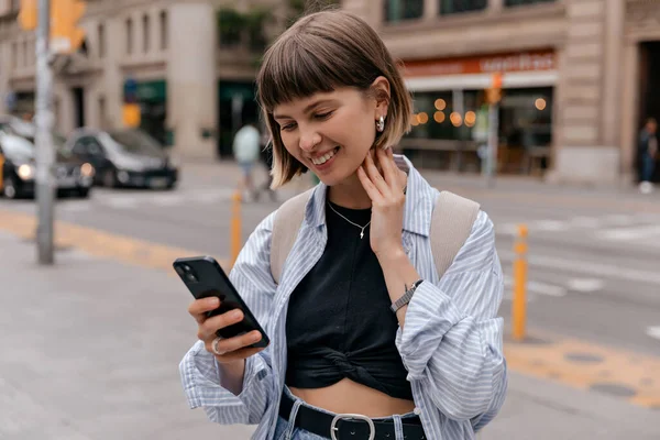 Senyum Manis Rambut Pendek Tersenyum Sambil Memegang Smartphone Kota Mengenakan — Stok Foto