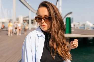 Çekici genç bir kadın sedyede yaz yürüyüşlerinden hoşlanıyor. Esmer, güneş gözlüğü, gömlek ve kot pantolon giyiyor. Yaz tatili kavramı.