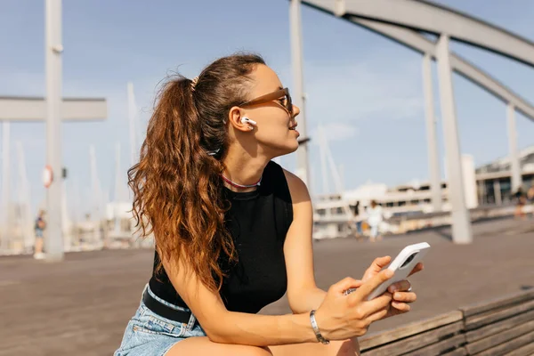 İskelede, yatların arkasında genç ve güzel bir kadının profil fotoğrafı. Kahverengi saçlı, gözlerini kapatan, sıcak yaz gününün tadını çıkaran bir kız. Yaz tatili kavramı