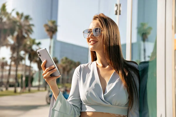 Smiling Attractive Girl Smartphone Her Hands Looks Away Relaxing Outdoors — Stok Foto