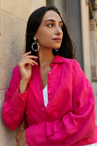 明るいヨーロッパの通りに立っている間脇を見てピンクのシャツを着て暗い髪を持つ魅力的な若い女性の外の写真を閉じます — ストック写真