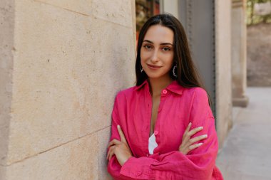 Neşeli, neşeli genç bir kadın dışarıda güneşli bir havada vakit geçiriyor. Esmer, pembe günlük gömlek giyiyor. Yaz tatili kavramı