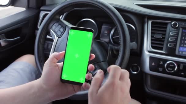 Man hand scrolling chromakey mobile phone with empty green screen in the car. Mockup touchscreen. Green smartphone display. — Stock Video